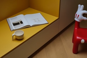 An open book and a white mug on a yellow-orange shelf