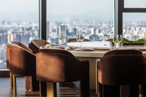 An elegant restaurant space with modern design elements, featuring armchairs upholstered in brown leather and a dining table 