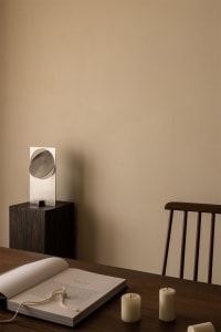 A minimalist interior design featuring a wooden table with candles and a book.