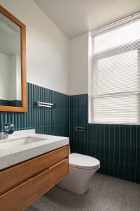 Modern bathroom interior with green tiles and wooden vanity.
