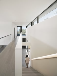 A modern indoor staircase with concrete steps, glass walls, and a view out to the outdoors.
