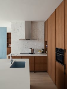 A modern residential kitchen with a white terrazzo countertop and minimalist design.