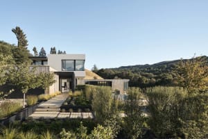 A modern minimalist residential exterior featuring glass windows and concrete materials.