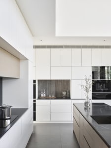 Modern kitchen featuring white marble countertops and aluminum appliances on black marble floor.