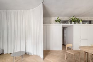 Minimalist apartment with white concrete walls and modern furniture.