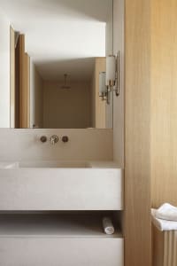 A modern, minimalist bathroom featuring a concrete countertop sink and wooden walls.