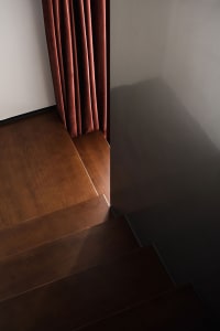 Contemporary wooden floor and staircase corner with a red curtain.