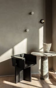 A sleek, modern metal stool in a contemporary living room setting.