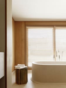 Modern bathroom interior with a wooden wall and a marble bathtub.