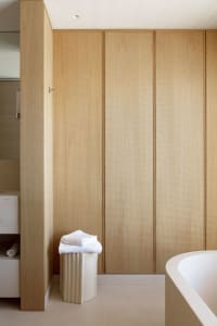A minimalist bathroom with wooden paneling and a terrazzo floor.