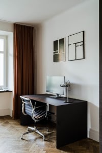 Modern minimalist home office setup with a metal desk, ergonomic chair, and framed abstract art on the wall.