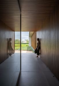 Woman standing in a minimalist living space with wooden paneling.