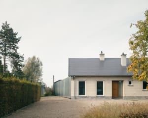 A residential exterior with white brick walls and a metal fence.