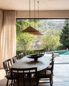 A modern residential dining room featuring a wooden table and chairs, with a large window overlooking a scenic outdoor view.
