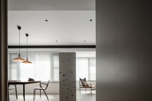 A minimalist modern dining space featuring concrete elements and contemporary furniture.