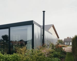 Modern house extension with large glass panels and a chimney