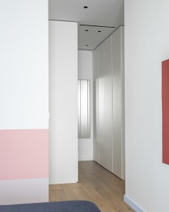 Modern bedroom with minimalist design featuring white walls and flooring.
