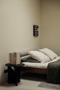 A minimalist bedroom featuring a wooden bed frame and white linens.