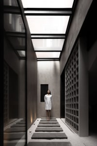 A minimalist interior space made of concrete and glass with a skylight.