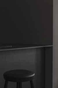 Black countertop with black stool against dark wall in minimalist interior