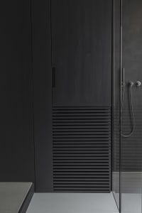 A modern bathroom with black wood elements and a minimalist aesthetic.