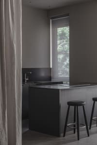 Modern minimalist kitchen with black cabinets, stainless steel appliances, and a black countertop.