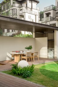 Modern patio with wooden flooring, green grass, and decorative plants.