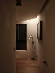 A minimalist interior design featuring metallic floor lamp, wooden floors, and smooth plaster walls.