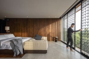 A modern bedroom featuring a comfortable bed and couch with white bedding and wood paneling.