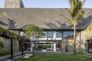 Modern residential exterior featuring a combination of concrete, natural stone, and greenery.
