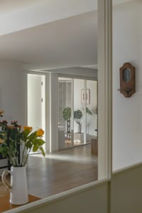 A modern living room with white walls, wooden flooring, and a vase of flowers.