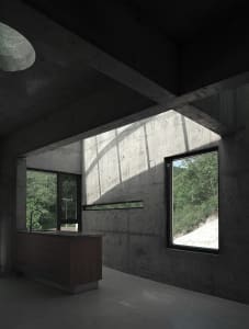 A modern kitchen with concrete walls and a dark interior design