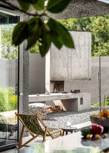 Modern outdoor living space with a concrete fireplace and stacked firewood.