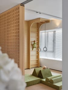Minimalist children's room with green furniture, wooden structure, and toys.