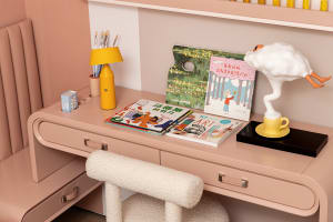 A modern casual home office with pink furniture and decorative elements.