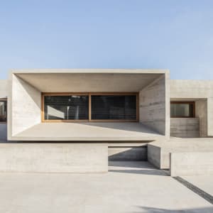 Modern building exterior featuring concrete walls and large windows on a bright day.