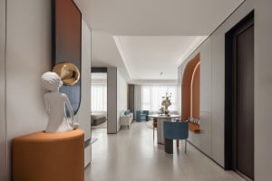 A modern minimalist living space featuring white walls and a dining area with a round table and blue chairs.