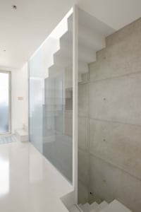 Minimalist interior design featuring a modern staircase with concrete and glass elements