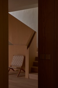Industrial-style interior with wooden stairs and a woven leather chair.