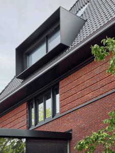 Modern house with black brick exterior and large windows.