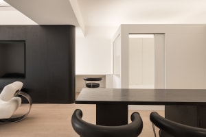 A minimalist residential interior with black and white furniture and wooden elements.