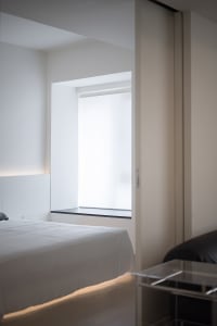 A minimalist bedroom with a white bed and walls