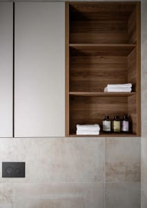 Minimalist bathroom featuring wooden shelves and ceramic tiles.