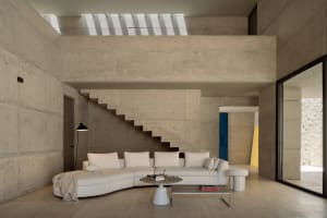 A modern interior living room with minimalist design, concrete walls, and a white sectional sofa.