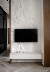 A minimalist living room with textured paper walls and a floating TV stand.