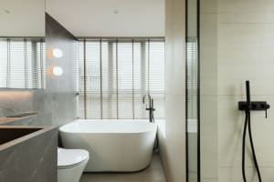 Modern minimalist bathroom featuring a white bathtub, terrazzo tiles, and a white toilet.