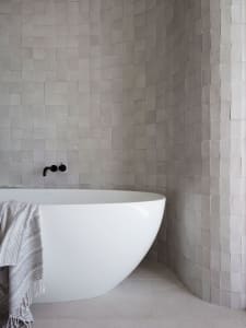 Modern minimalist bathroom with concrete tiles and a white bathtub.