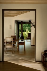 Modern minimalist dining room featuring a natural wood dining table and chairs, with a view of the outdoors through large win