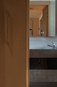 Contemporary bathroom interior featuring a concrete countertop with a sleek faucet and a mirror reflecting the ceiling.