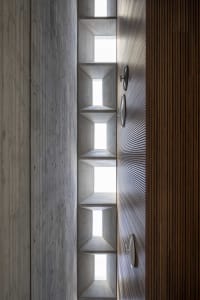 A modern interior with concrete walls and wooden elements, featuring cut-out spaces and geometric shapes.